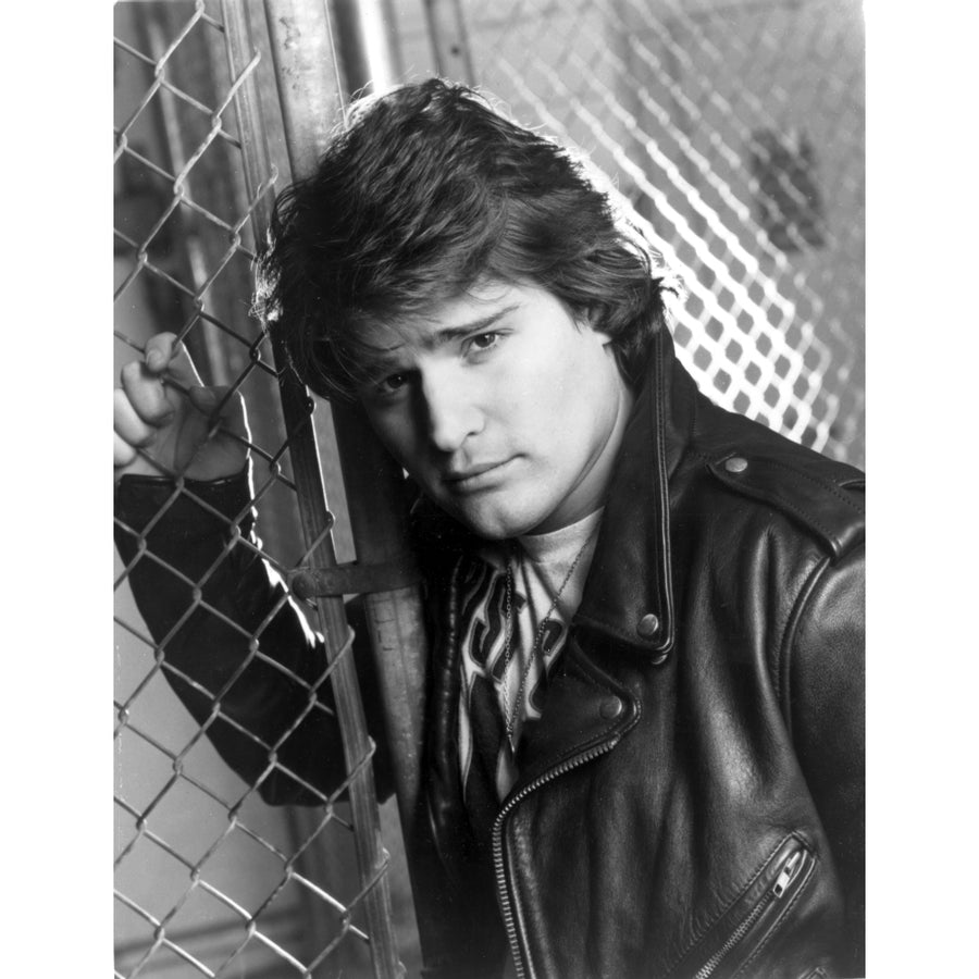 Peter Deluise wearing a leather jacket leaning on a wire fence Photo Print Image 1