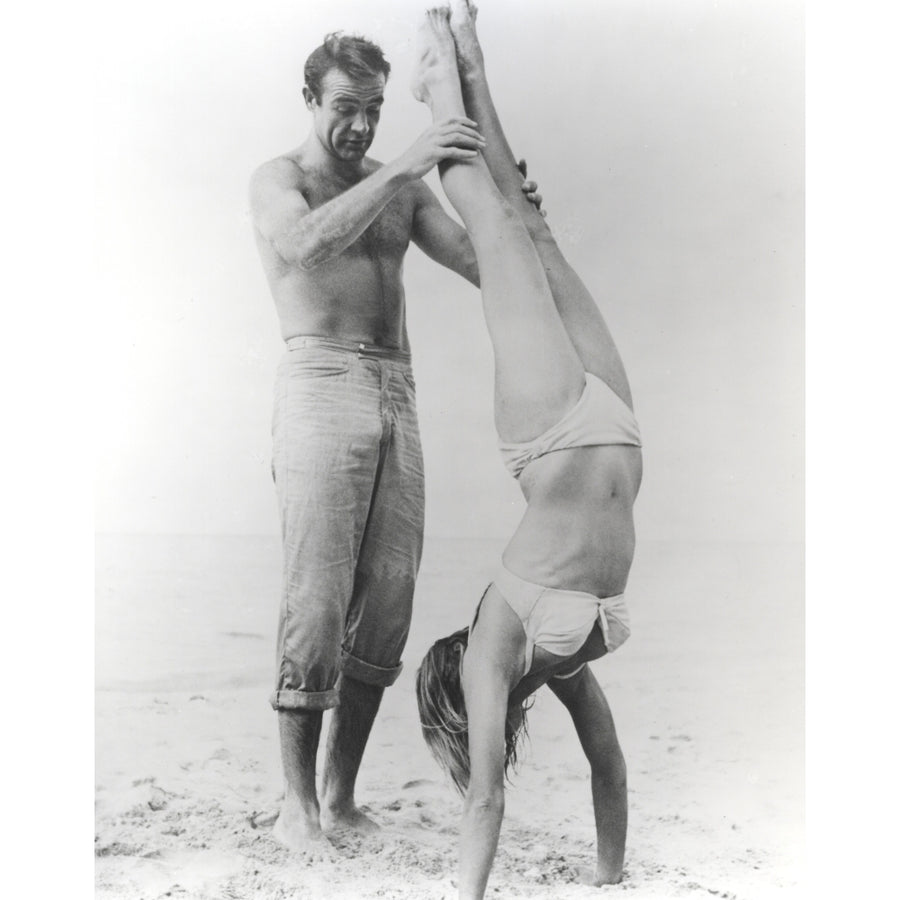 Sean Connery helping a woman in a bikini do a handstand Photo Print Image 1