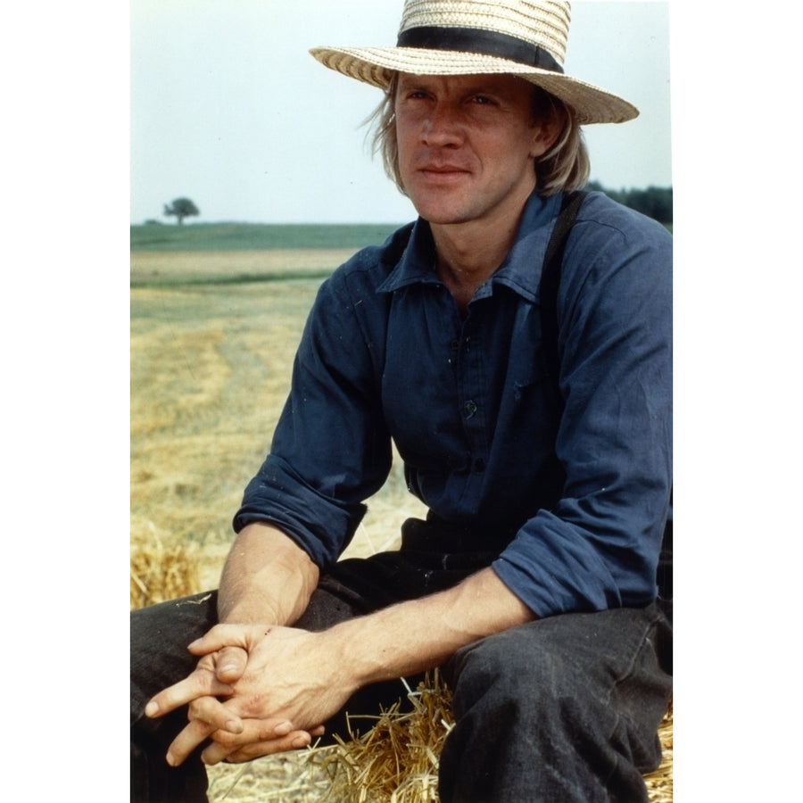 Alexander Godunov sitting on a Hay Stack wearing Blue Long Sleeves and a Hat Photo Print Image 1