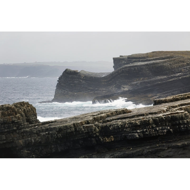 Rugged dark rocky cliffs with waves and fogged sky; Kilkee County Clare Ireland Poster Print Image 1