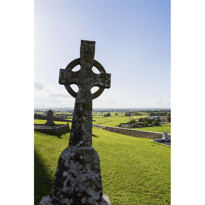 Celtic cross on grassy hill with stone wall under blue sky; Cashel County Tipperary Ireland Poster Print Image 1