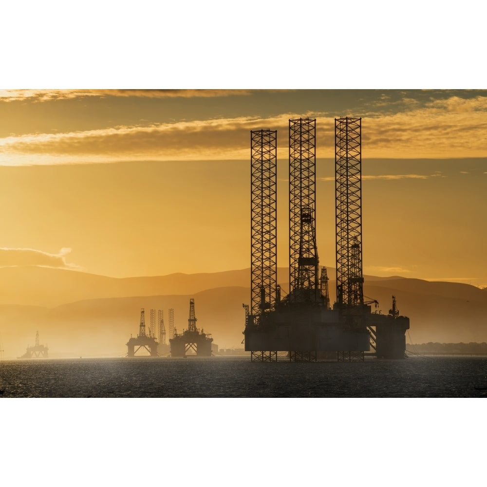 Oil drilling rigs out in the ocean with a view of the coastline and golden sunset; Cromarty Invergordon Scotland 38 x 24 Image 1