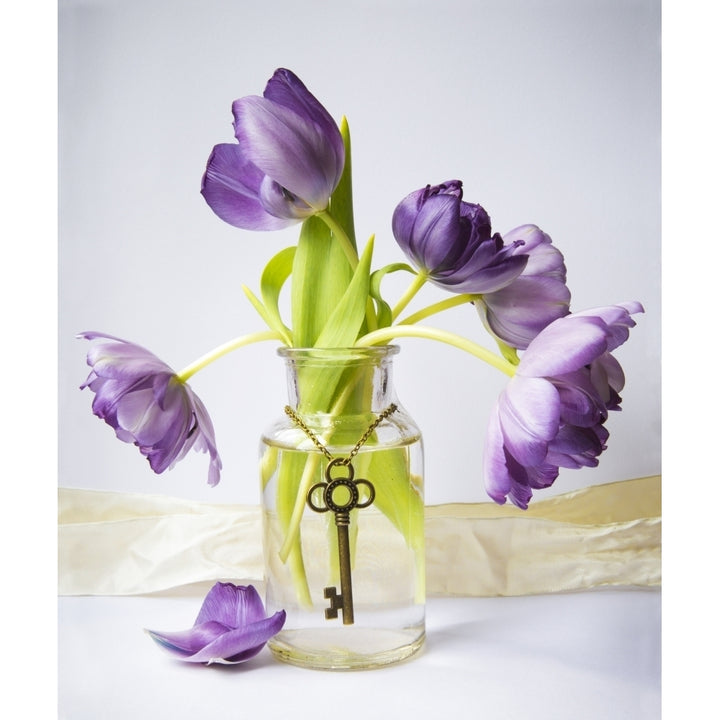 Purple tulips in a vase with an antique key hanging gracefully around the vase Image 1