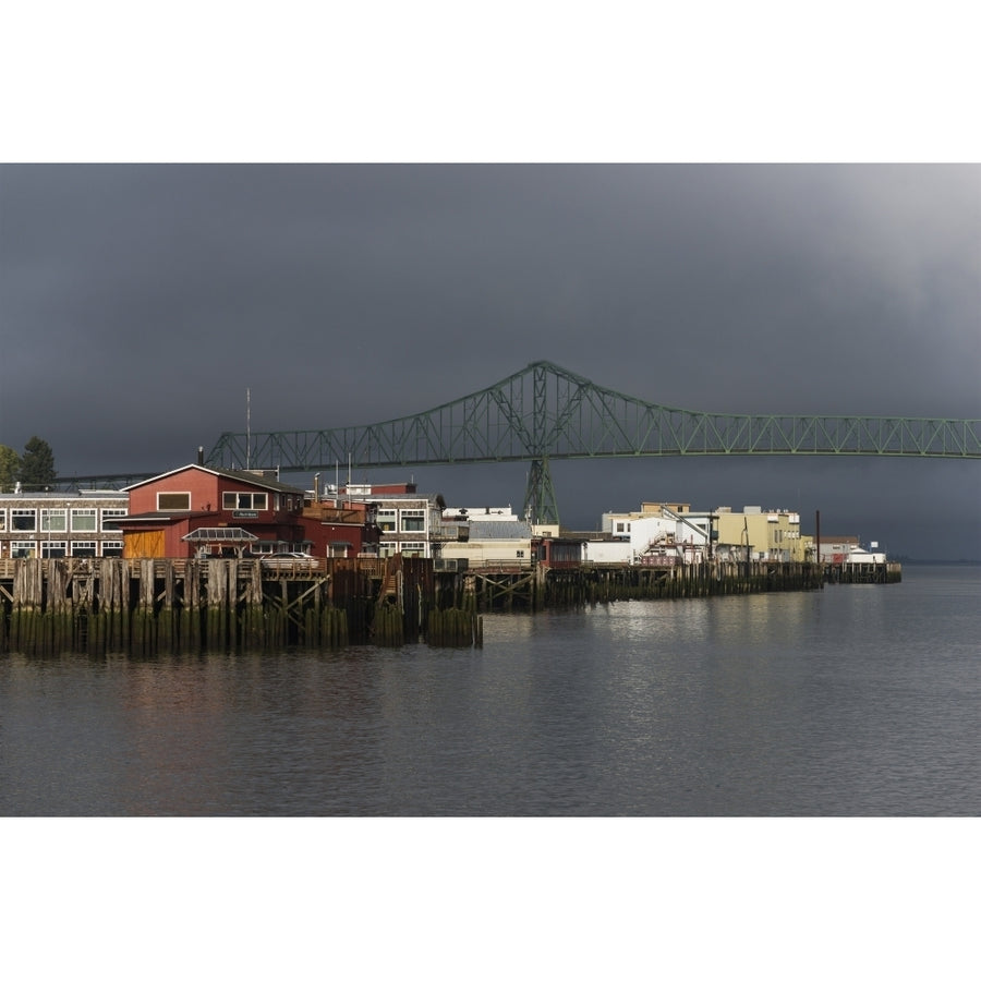 Sunlight warms the riverfront with storm clouds over the Astoria-Megler bridge; Astoria Oregon United States of Americ Image 1