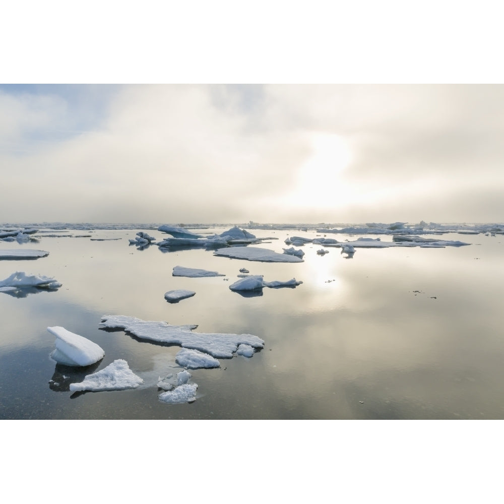 A foggy sunset over the Arctic Ocean illuminates icebergs on a partly clear and calm evening; Barrow North Slope Alask Image 2