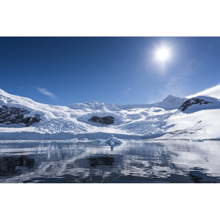 Bright sun and snow on the mountains reflected in the water of Neko Harbour; Antarctica Poster Print by Deb Garside / De Image 1