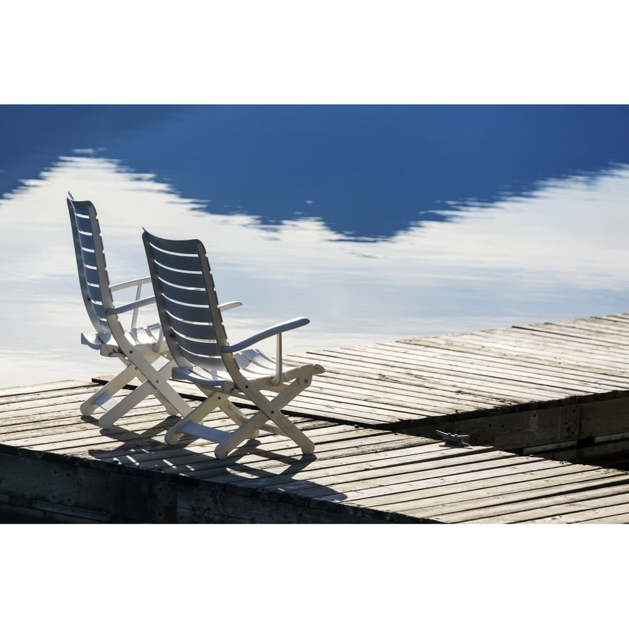 Two white wooden deck chairs on wooden boat dock reflecting in the water; Invermere British Columbia Canada Poster Pri Image 1