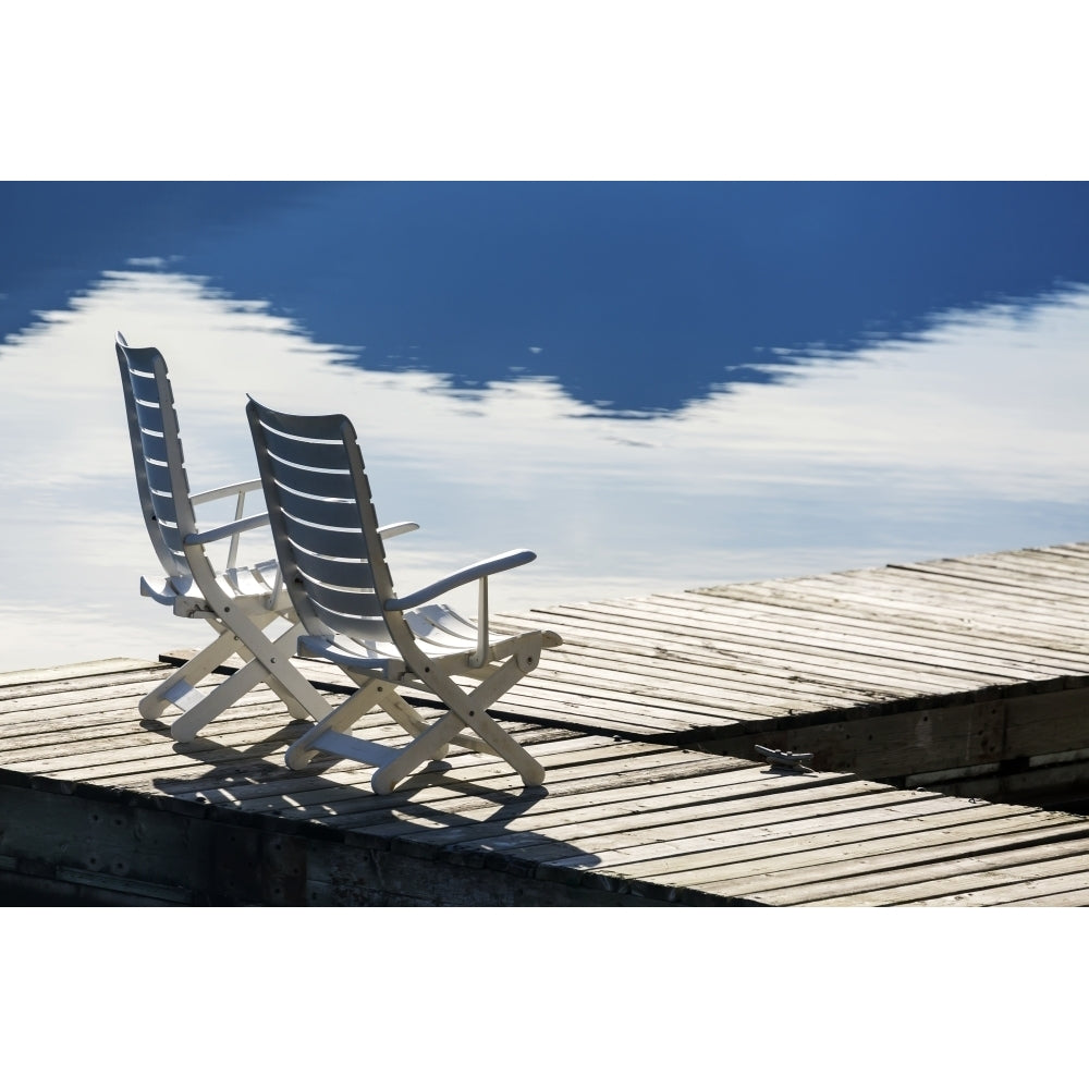 Two white wooden deck chairs on wooden boat dock reflecting in the water; Invermere British Columbia Canada Poster Pri Image 2