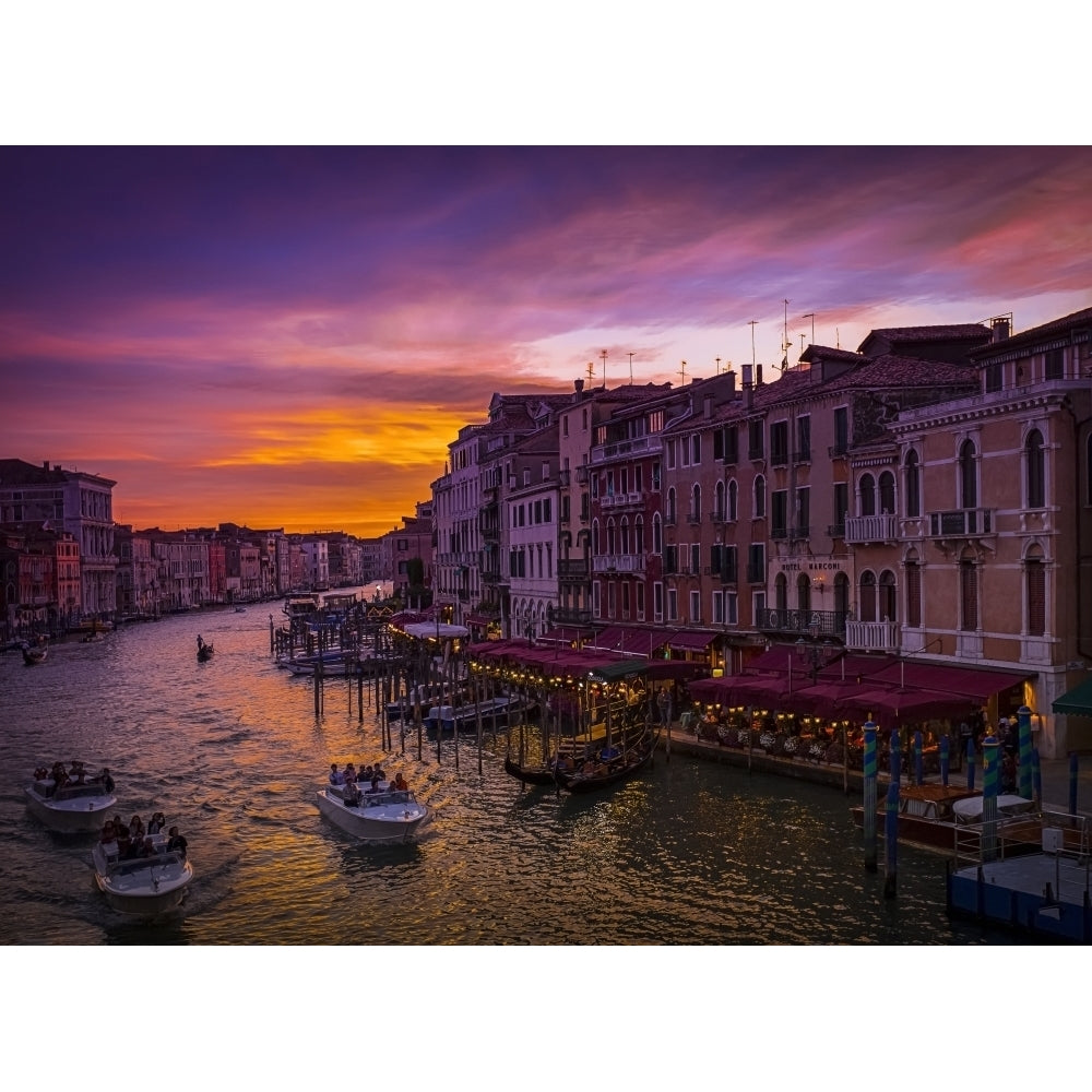 A dramatic and colourful sunset over the canal and buildings with water taxis in the canal; Venice Italy Poster Print Image 2