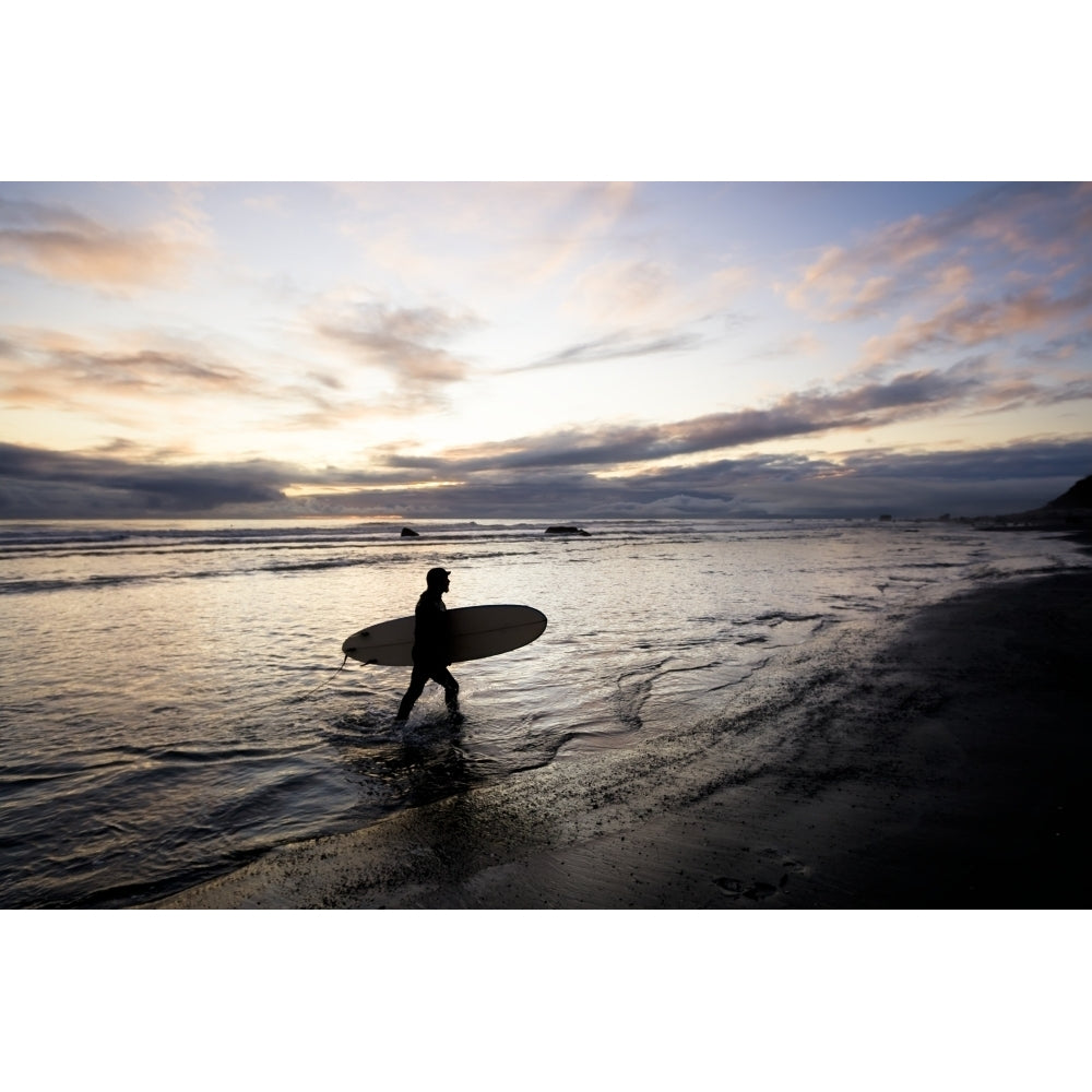 Silhouette Of A Surfer Carrying A Surfboard Back To Shore At Sunset; Alaska United States Of America by Scott Dickerson Image 1