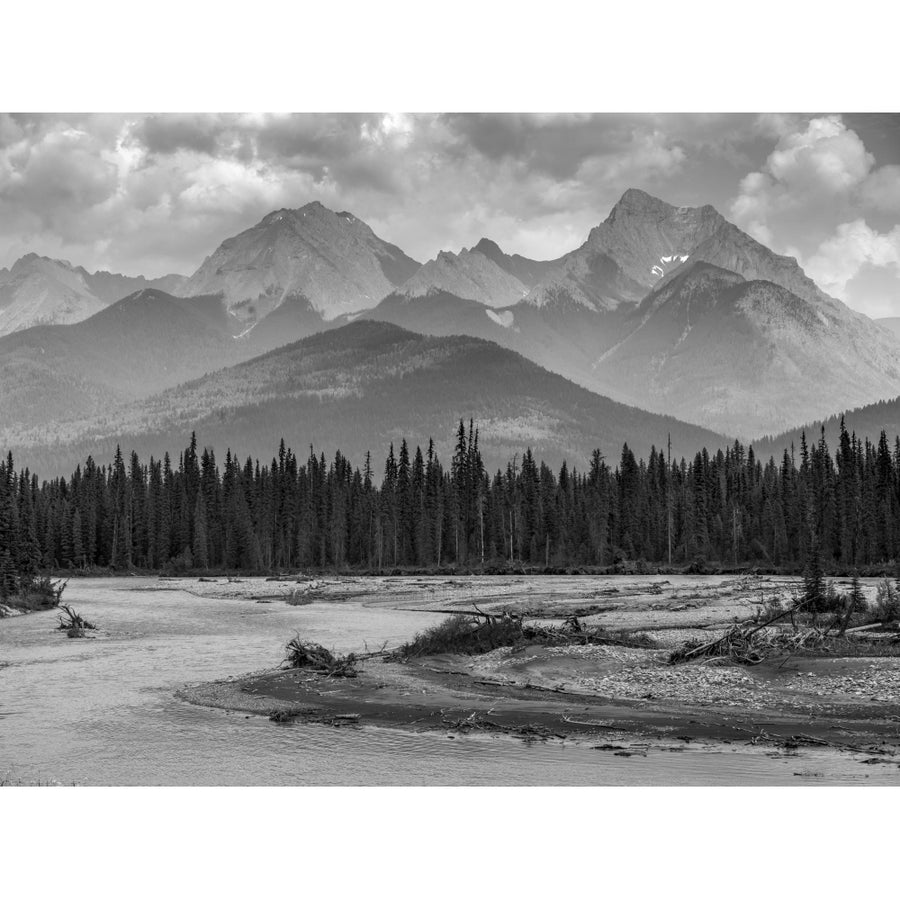 Black and white landscape of the rugged Canadian rocky mountains with a forest and a flowing river in the foreground; Image 1