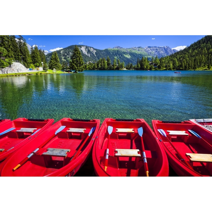 Red boats lined up at Champex Lake under blue sky with a mountain range in the background; Champex Valais Switzerland by Image 1