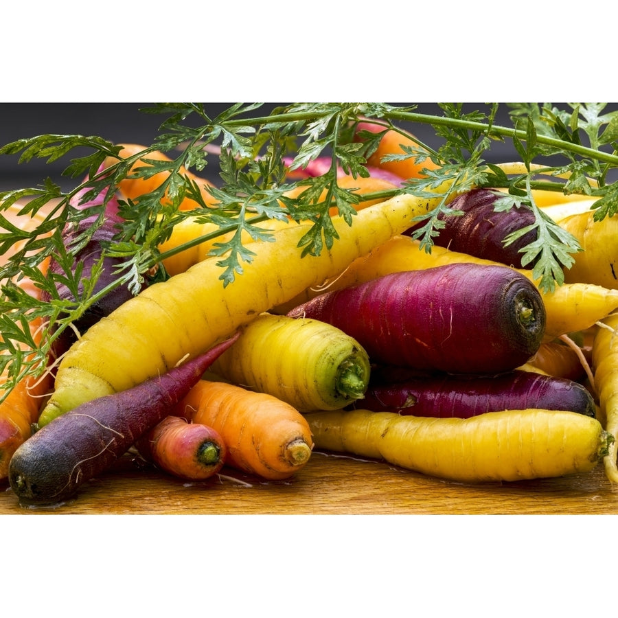 Variety of coloured fresh carrots laying on a wooden surface by Michael Interisano / Design Pics Image 1