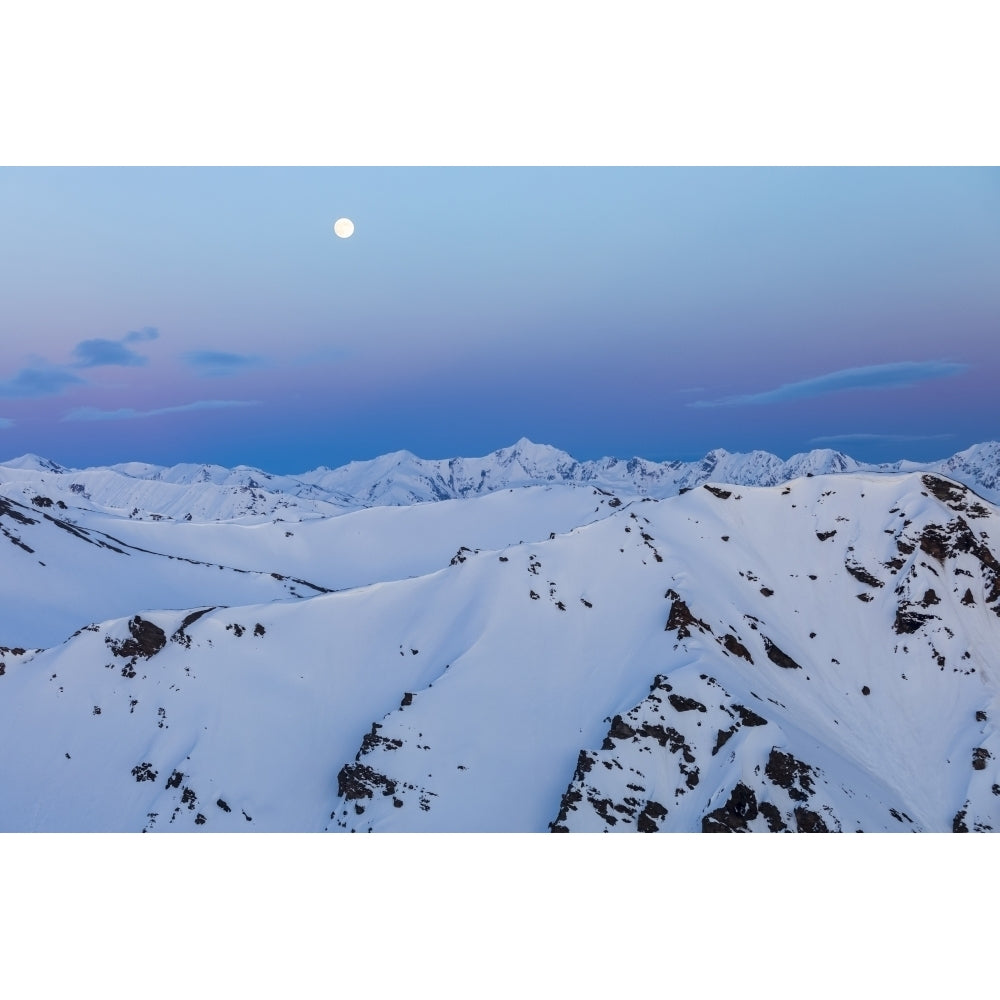 The moon rises over snowy mountain ridges after sunset in the Alaska Range; Alaska United States of America Poster Print Image 1