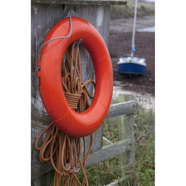 An Orange Life Preserver Ring And Rope Hanging On A Wooden Shed Wall; Northumberland England Poster Print Image 1