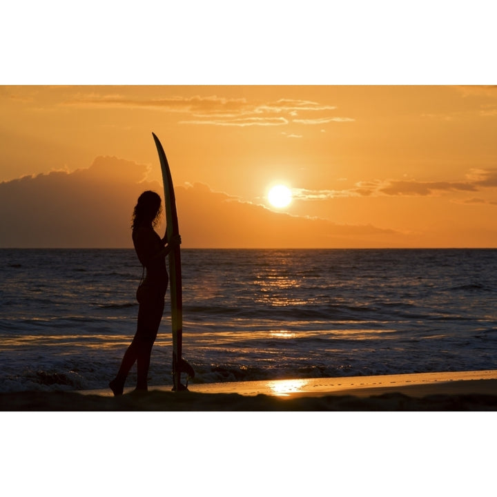 Hawaii Female Surfer On Beach Silhouetted Against Orange Sunset Over Ocean. Poster Print Image 2