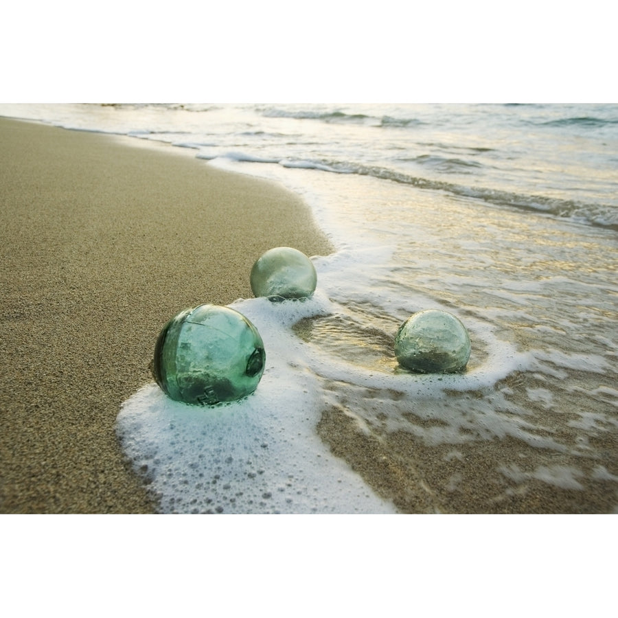 Three Glass Fishing Floats Roll On The Sandy Shoreline With Ripples Of Water And Seafoam Poster Print Image 1