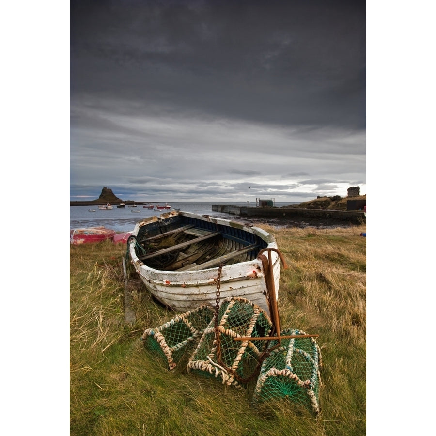 A Weathered Boat And Fishing Equipment Sitting On The Shore With Lindisfarne Castle In The Distance; Lindisfarne Northu Image 1