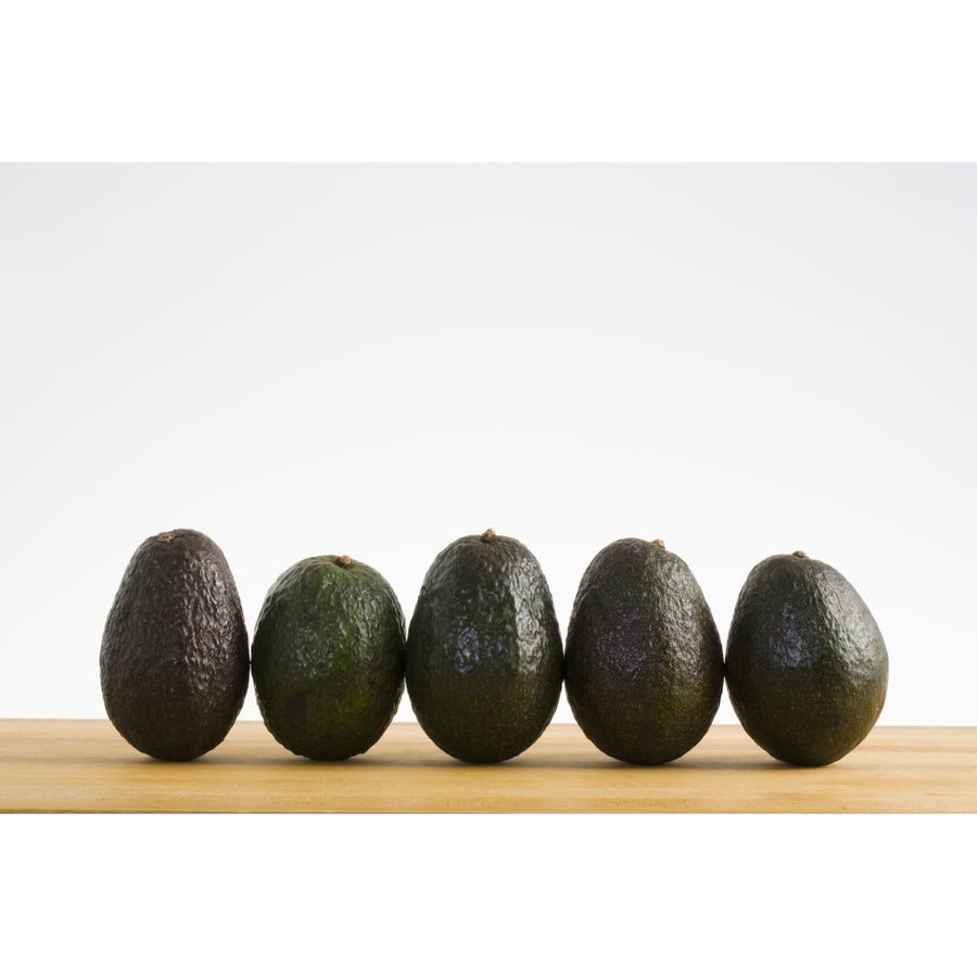 A Row Of Avocados Standing Upright On A Wooden Board; Calgary Alberta Canada Poster Print Image 1