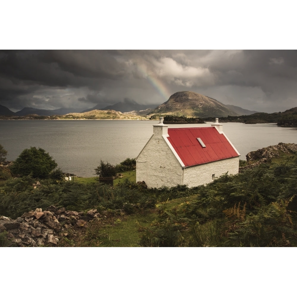 A Cottage With A Red Roof On The Waters Edge With A Rainbow In The Distance Image 1