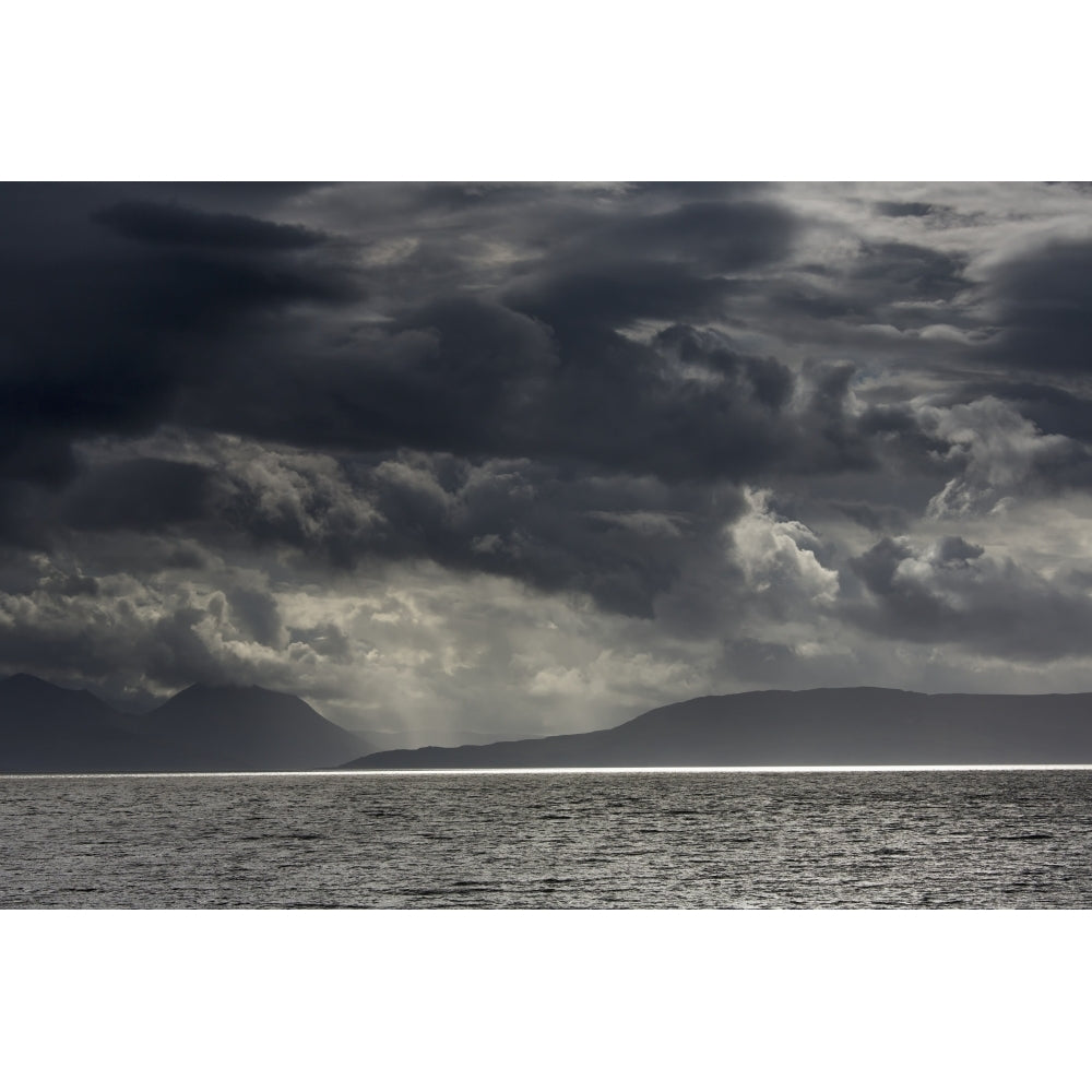 Dramatic sky with dark storm clouds over the ocean and a view of a silhouette of the coastline;Applecross peninsula scot Image 2