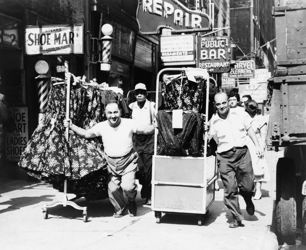 Men Pulling Racks Of Clothing On Busy Sidewalk In Garment District History Image 1