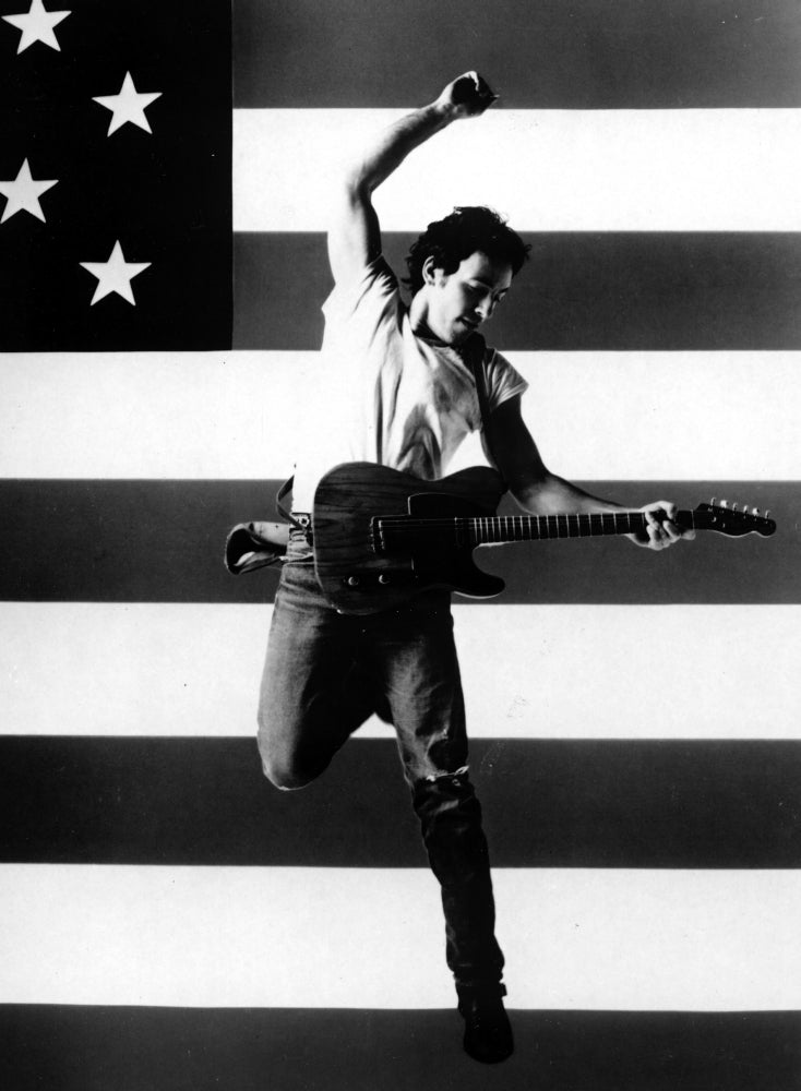 Bruce Springsteen playing guitar in front of an American flag Photo Print Image 1