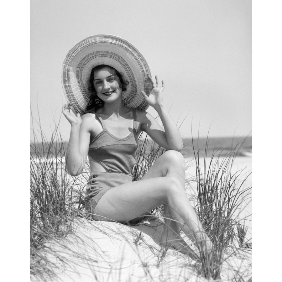 1920s-1930 Smiling Bathing Beauty Wearing Straw Hat Sitting On Beach Sand Dune Looking At Camera Print By Vintage Image 1