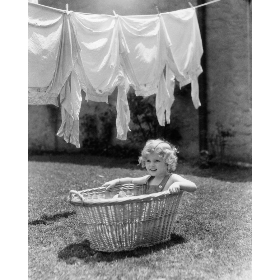 1930s-1940s Girl Outdoors Sitting In Laundry Basket Under Clothesline Full Of Shirts Print By Vintage Collection Image 1