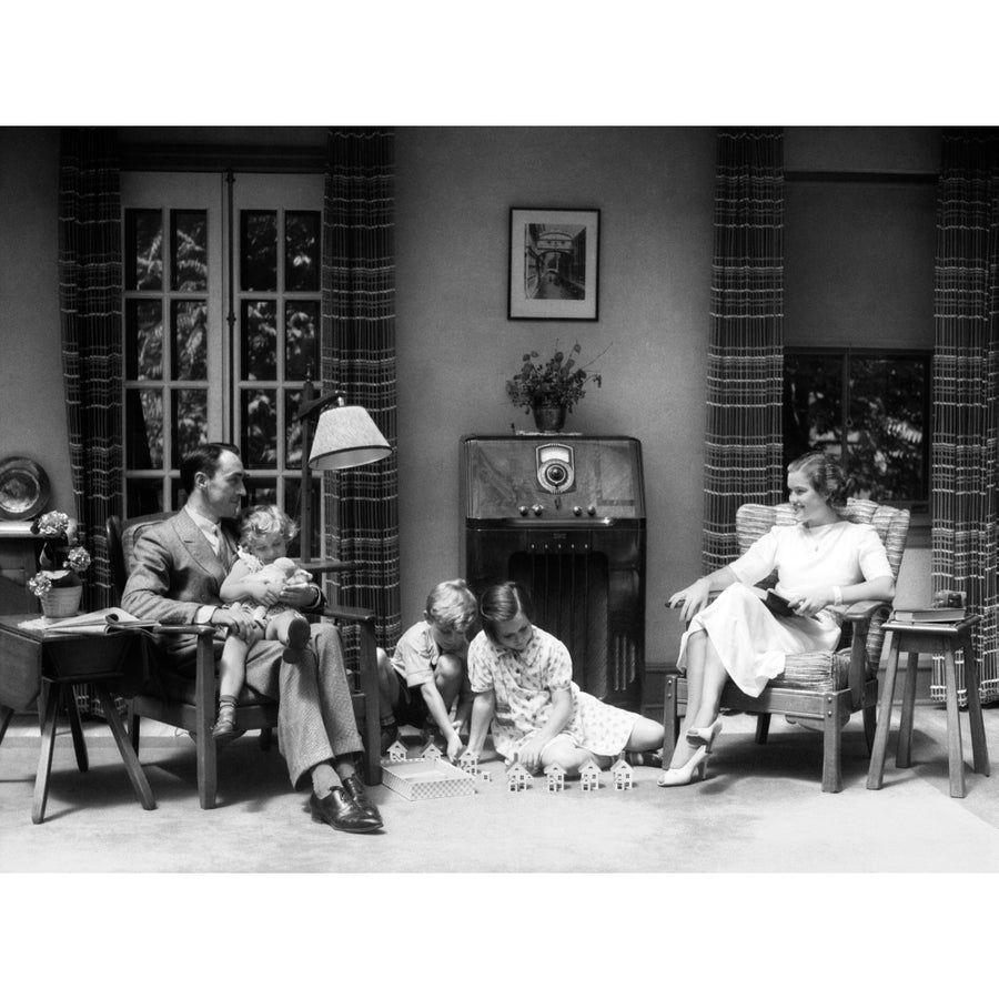 1930s-1940s Family In Living Room Listening To Radio While Children Play With Toy Houses On Floor Print By Vintage Image 1