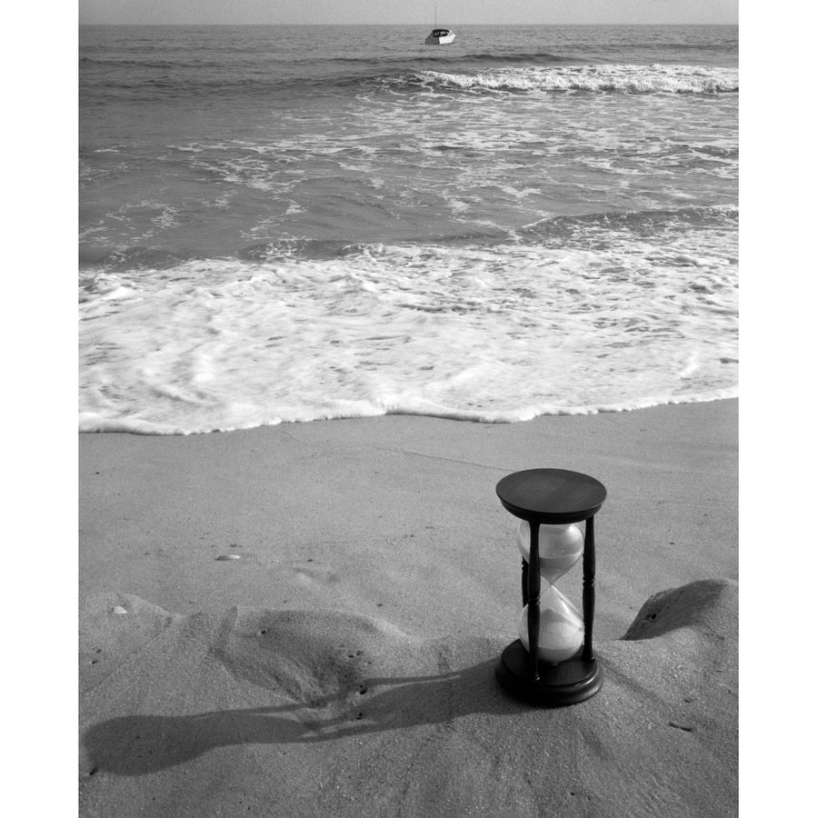 1960s Still Life Of Hourglass At Edge Of Beach Sand With Waves Washing Up On Shore And Power Boat Passing Offshore Image 1