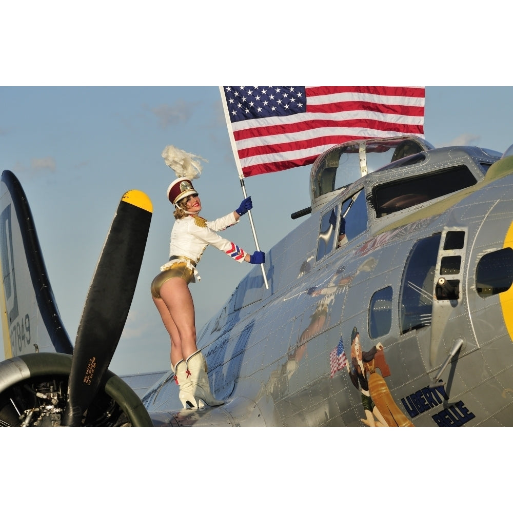 1940s style majorette pin-up girl on a B-17 bomber with an American flag Poster Print Image 1