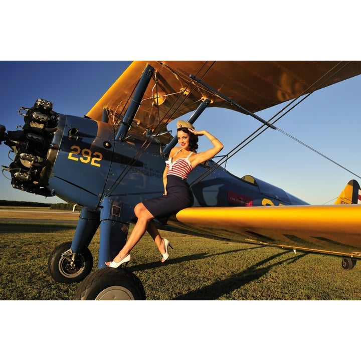 1940s style pin-up girl sitting on the wing of a Stearman biplane Poster Print Image 1