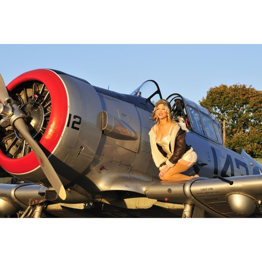 1940s style aviator pin-up girl posing with a vintage T-6 Texan aircraft Poster Print Image 1