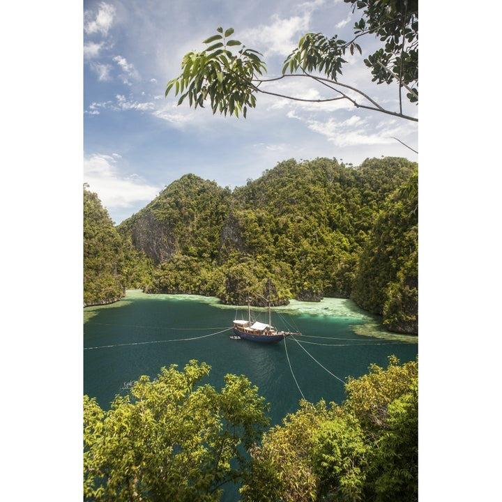 Rugged limestone islands frame an Indonesian pinisi schooner Poster Print Image 1