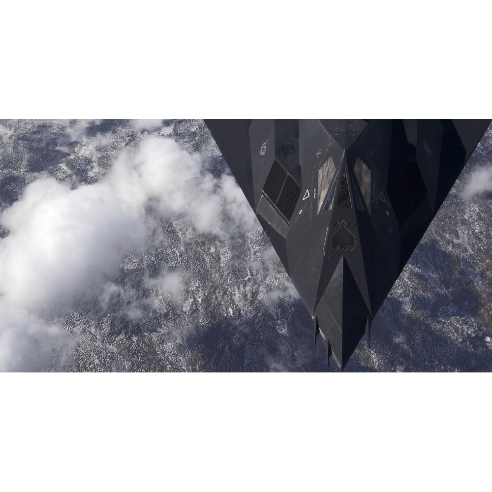 An F-117A Nighthawk flies high over the mountains Poster Print Image 1