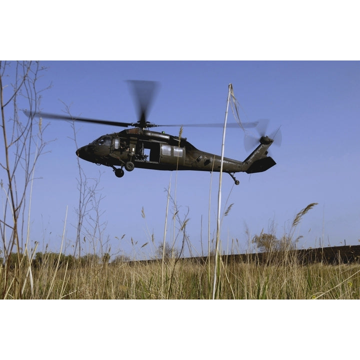 A U.S. Army UH-60 Black Hawk helicopter prepares to pick up soldiers Poster Print Image 1