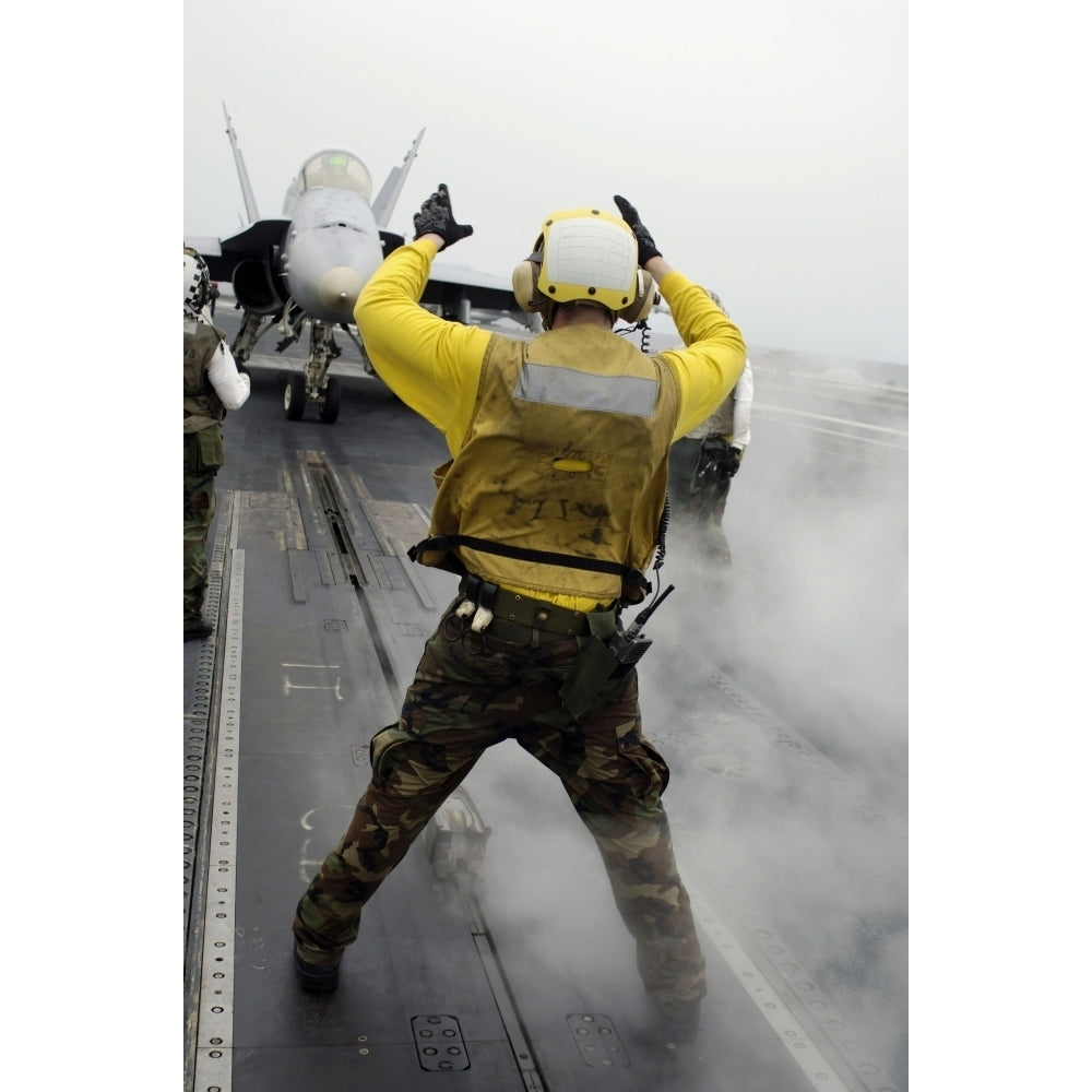 An aircraft director signals a F/A-18C Hornet on the flight deck of USS Kitty Hawk Poster Print Image 1