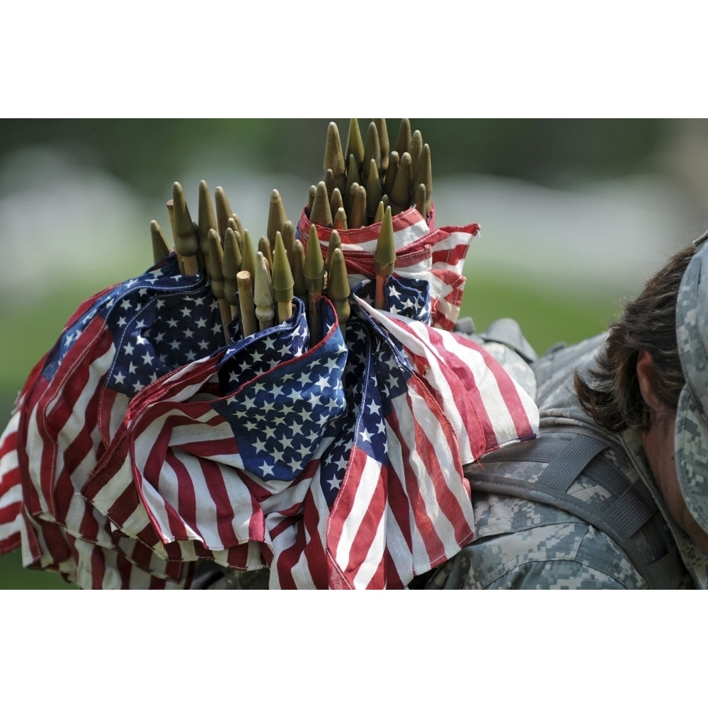 An Army soldiers backpack overflows with small American flags Poster Print Image 1