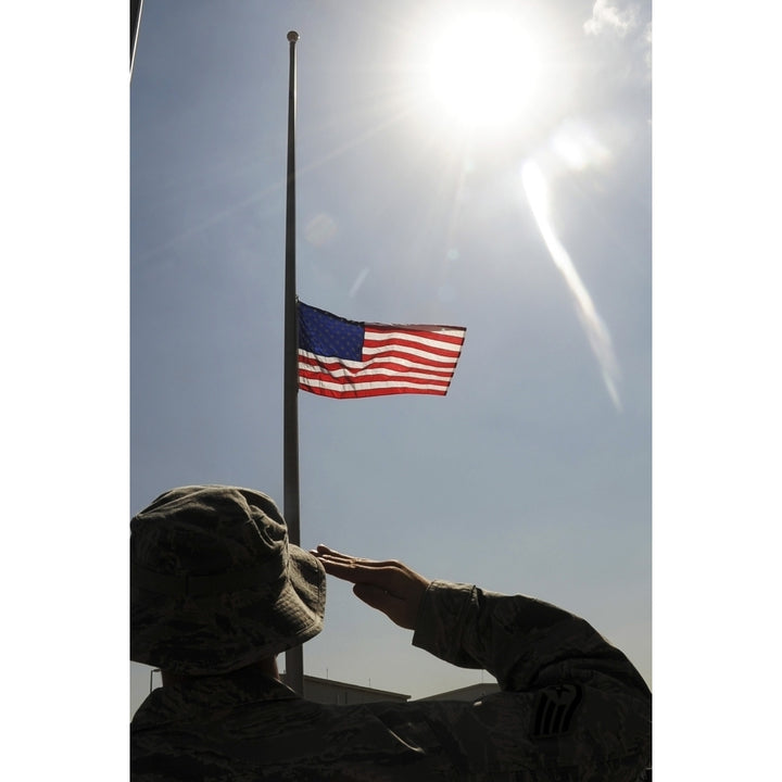 An Airman salutes the American flag that is flying at half-mast Poster Print Image 2