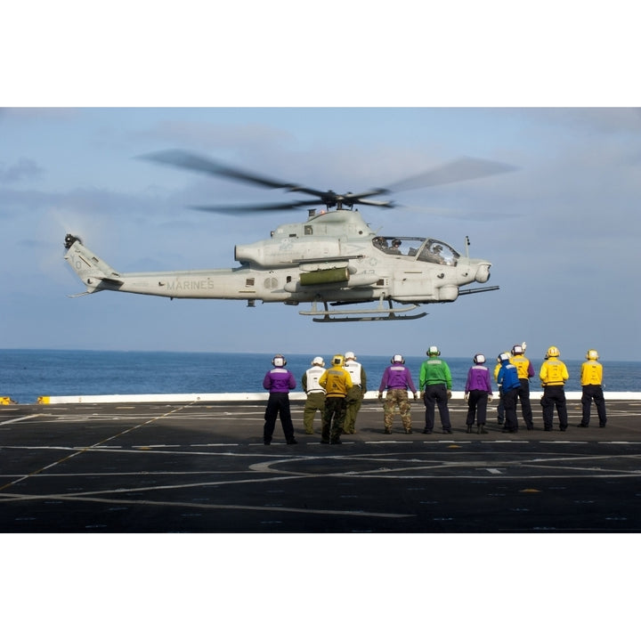 Sailors and Marines watch an AH-1Z Viper attack helicopter lift off the flight deck of USS Orleands Print Image 1