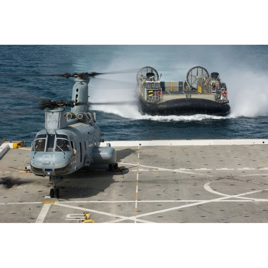 A hovercraft approaches USS Orleans as a CH-46E Sea Knight sits on the flight deck Poster Print Image 1