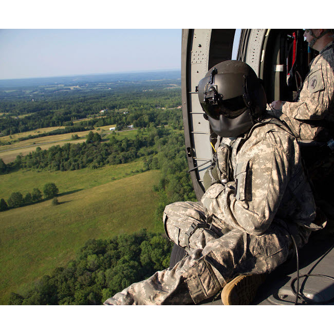 An Army crew chief looks out the door of a UH-60 Black Hawk helicopter Poster Print by Stocktrek Images Image 1