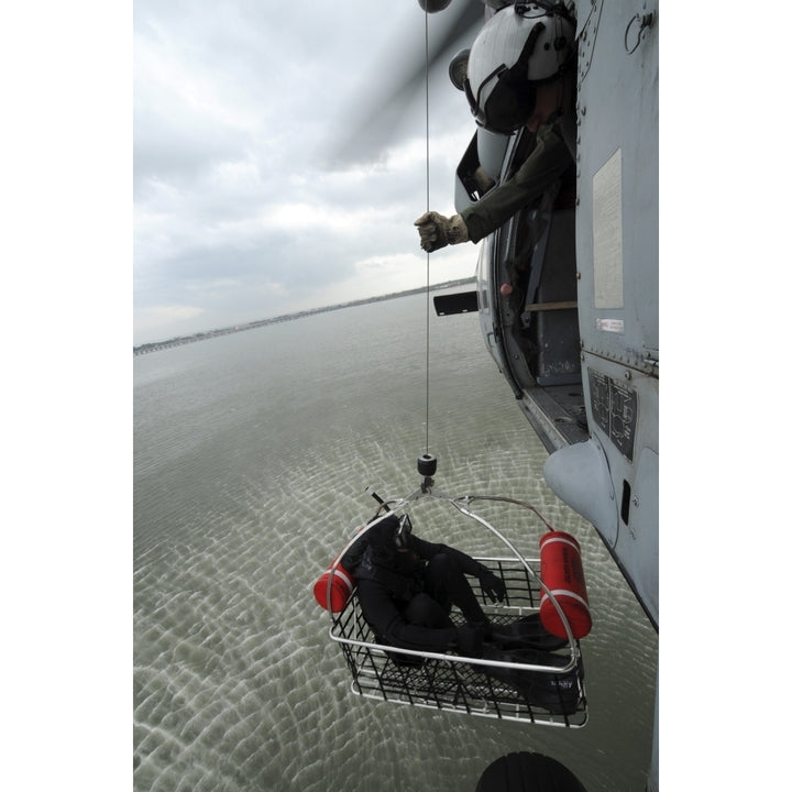 Naval Air Crewman hoists a rescue basket into an MH-60S Sea Hawk helicopter Poster Print Image 1