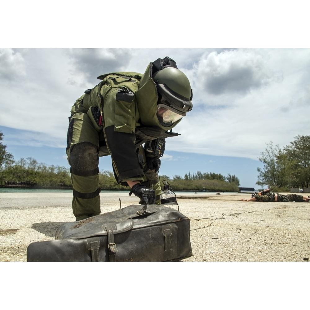 Soldier dressed in bomb suit inpecting a simulated improvised explosive device. Poster Print by Stocktrek Images Image 1