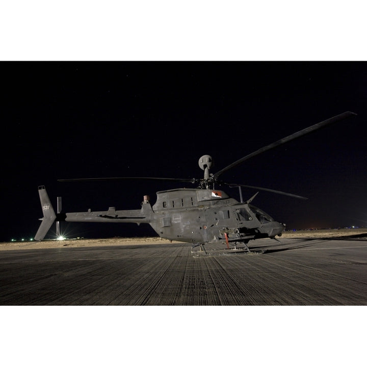 An OH-58D Kiowa sits on its pad at night Poster Print Image 1