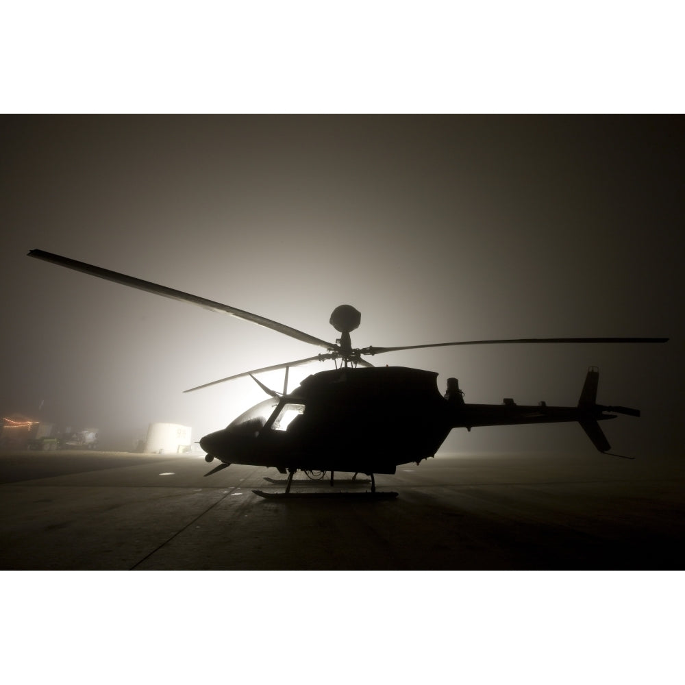 The illumination from the bright light silhouettes a OH-58D Kiowa helicopter during thick fog Poster Print Image 2