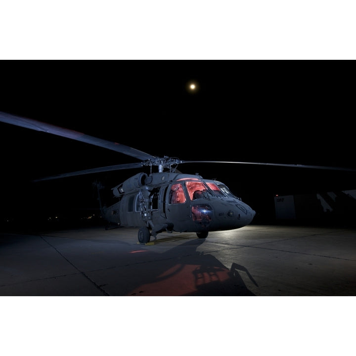 A UH-60 Black Hawk helicopter parked on the flight line under a full moon Poster Print Image 2