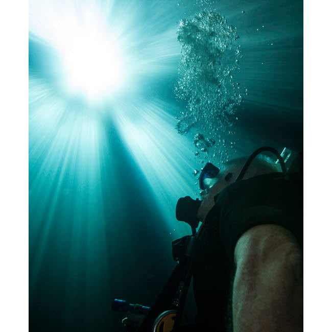 A scuba diver surfacing and looking up into the light Poster Print by Michael Wood/Stocktrek Images Image 2